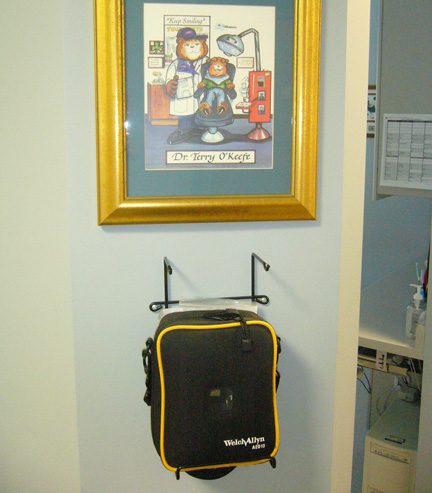 Automated External Defibrillator hanging on a wall under a painting given to Dr. O'Keefe at Terrance J. O'Keefe, DDS, LLC in Penfield, NY