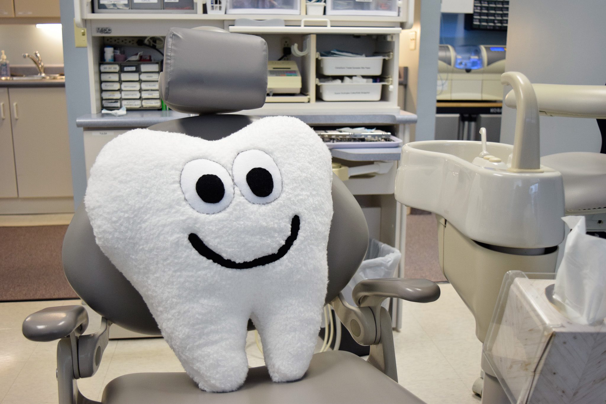 A cartoon tooth pillow sitting on a gray dental chair at Terrance J. O'Keefe, DDS, LLC in Penfield, NY